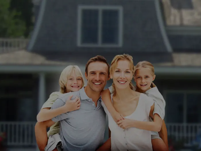 A family of four smiling in front of their home